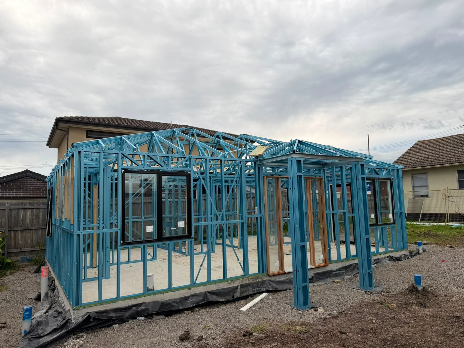Completed steel frame with roof trusses and window openings on a single-storey home in Melbourne